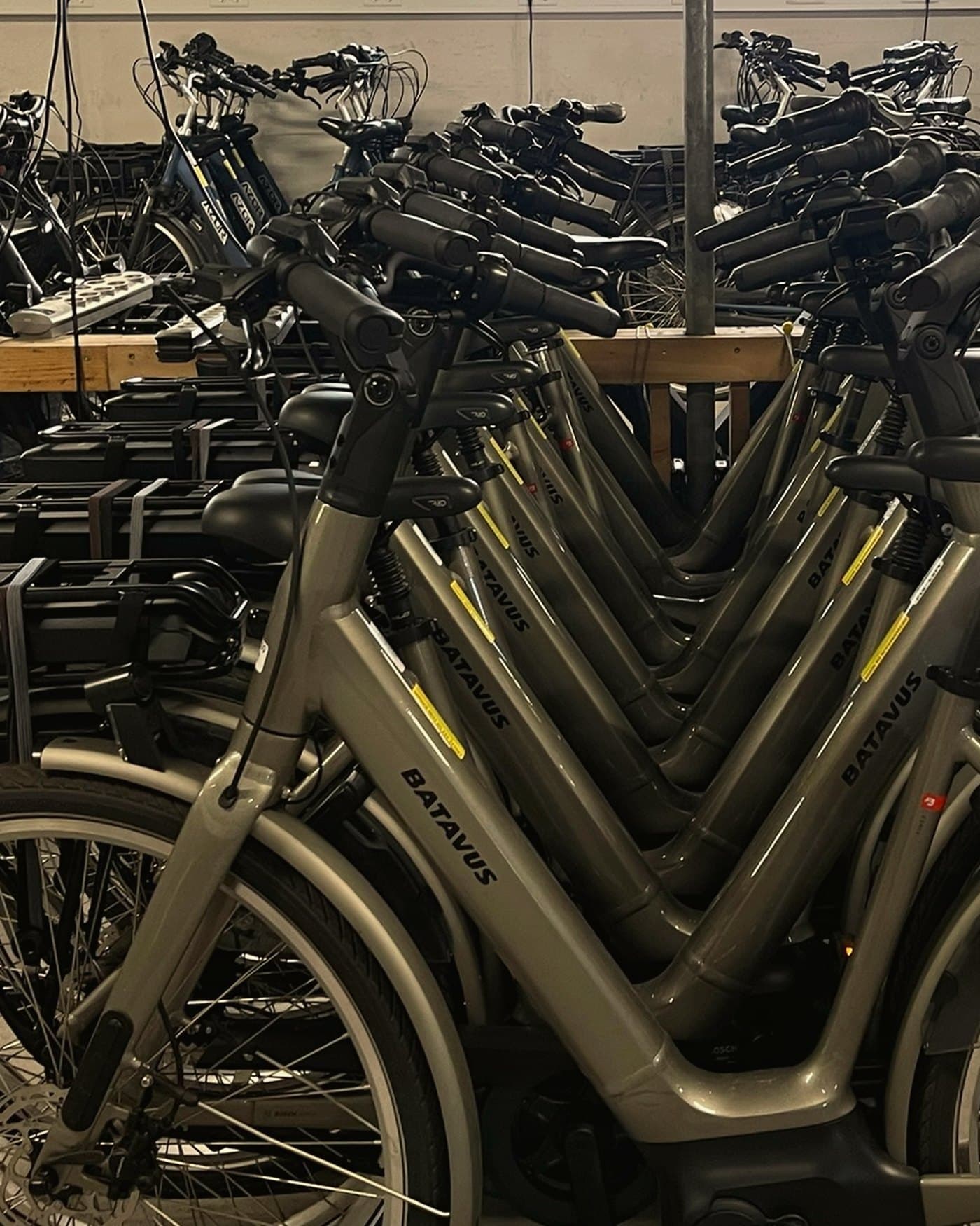 Verhuurfietsen dicht naast elkaar in een rek, van opzij gezien.